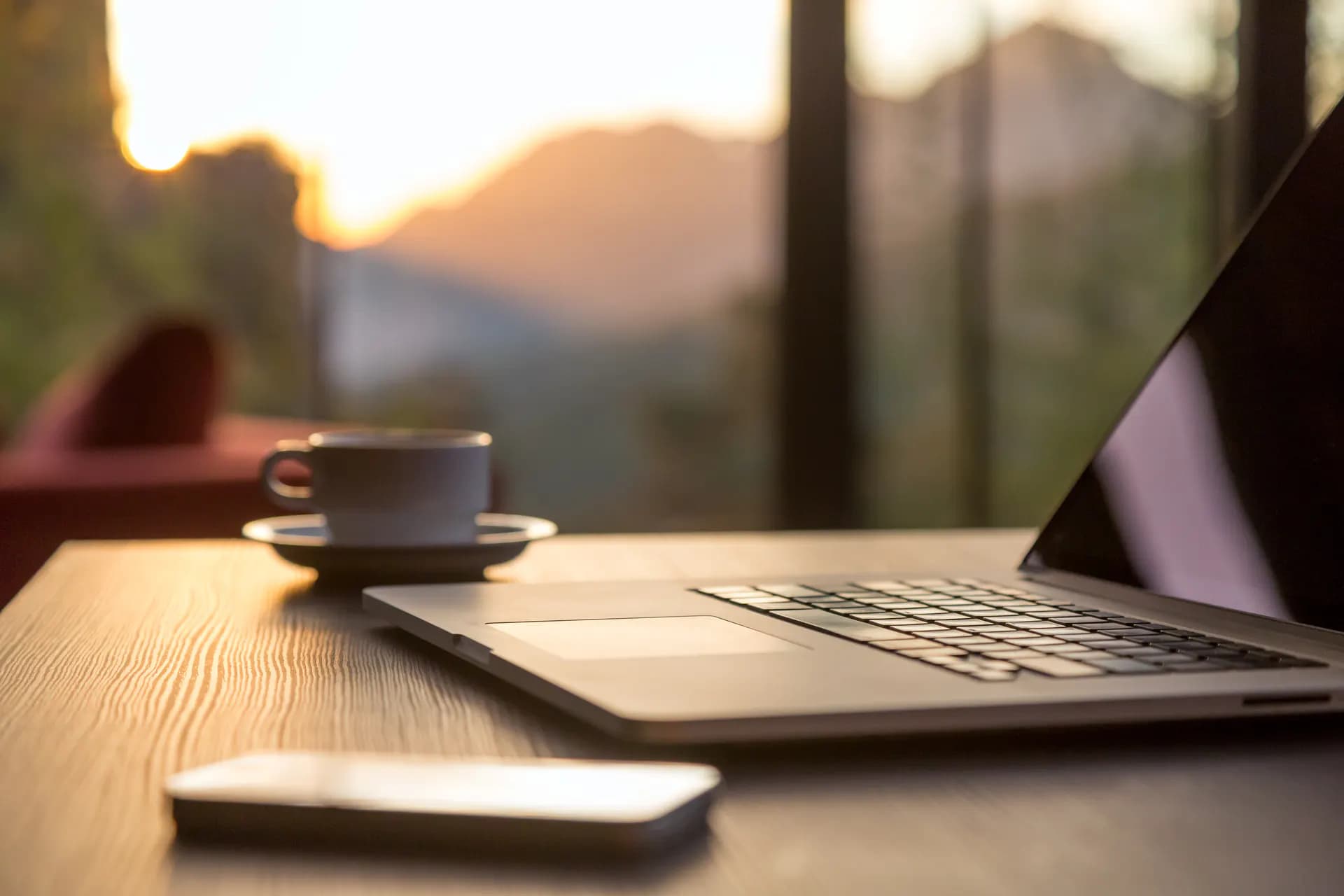 Laptop und Tasse auf einem Schreibtisch im warmen Licht